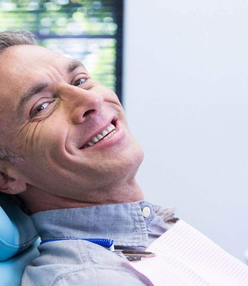 Male dental patient leaning back in chair and smiling