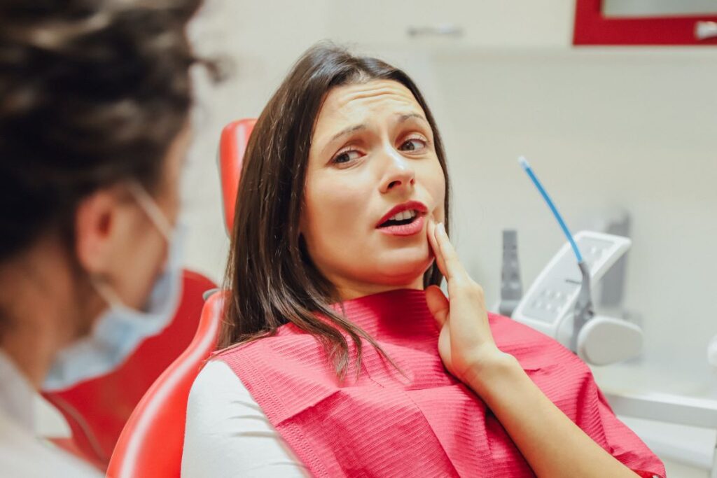 A woman holding her jaw in pain.